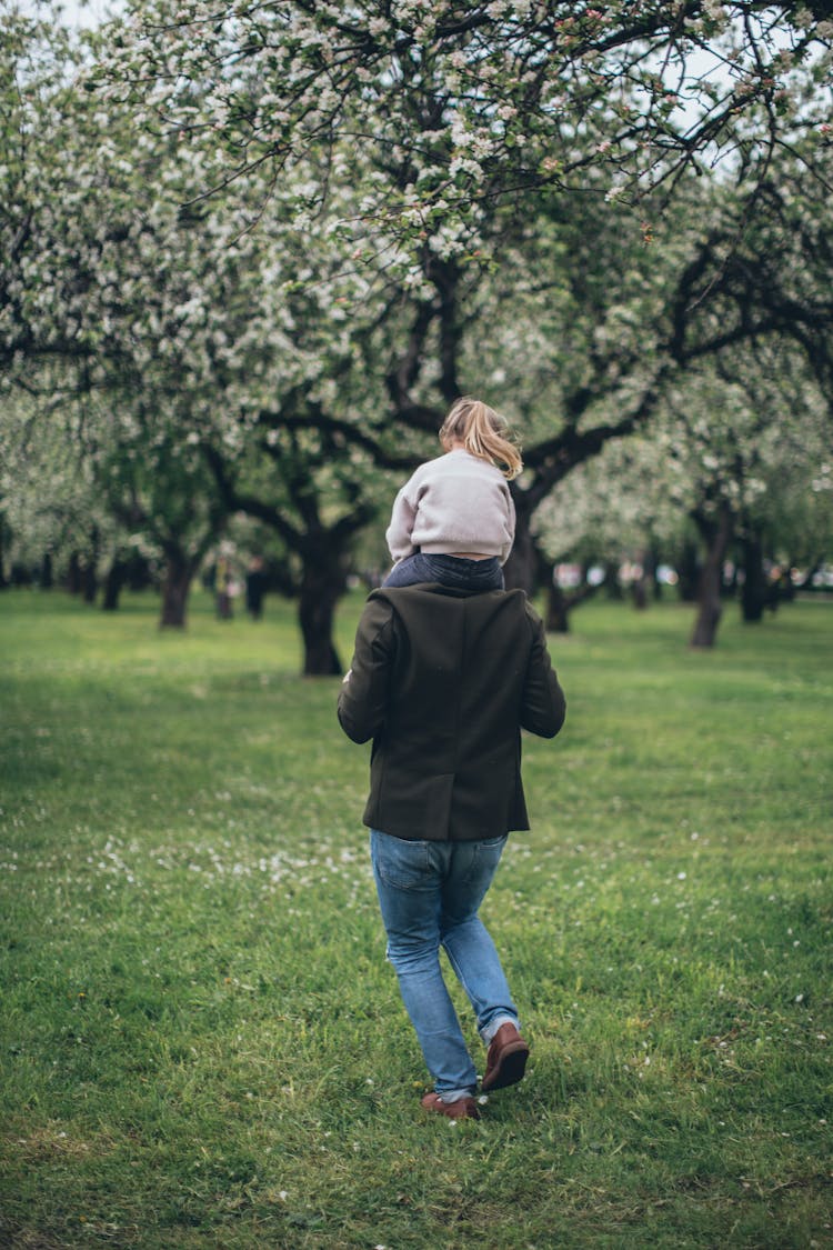 A Man Carrying A Child On His Shoulders