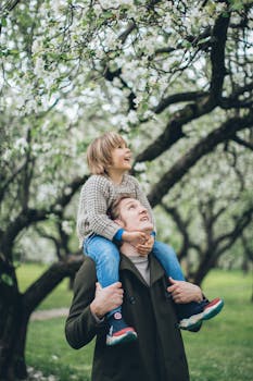 父亲在果园花开时扛着儿子，捕捉快乐的春天纽带