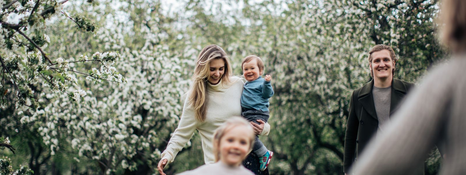 A joyful family enjoys a playful day outdoors amidst blossoming trees in spring.