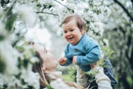 在开满鲜花的春日花园里，一位快乐的母亲抱着她快乐的孩子，捕捉到了温柔的瞬间