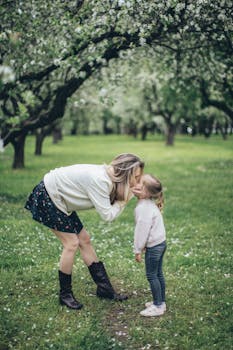 在果园盛开的时节，母亲亲吻着女儿，捕捉家庭的爱与自然