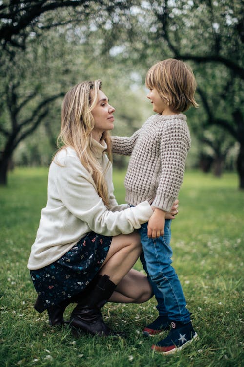 A Mother and Child Standing on Grass Field while Looking at Each Other