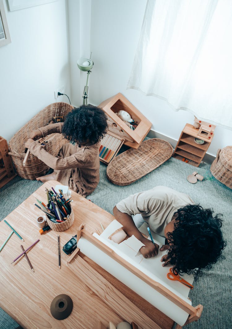 Unrecognizable Black Siblings Drawing On Paper Sheet In Living Room