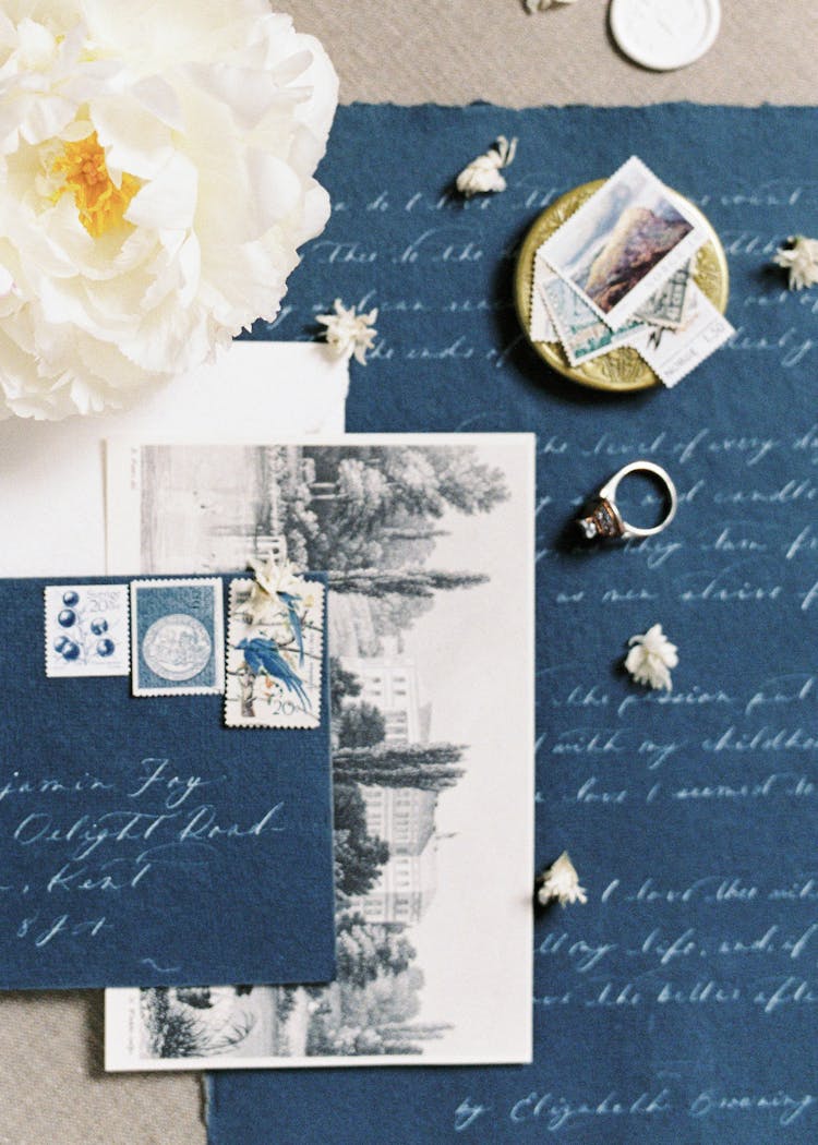 Post Card Beside Ring On Blue Sheet Of Paper