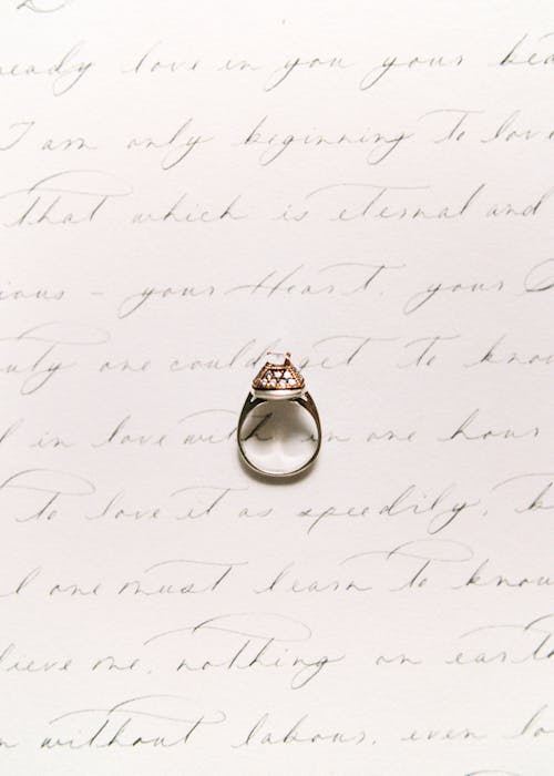 Diamond Ring on Top of White Sheet of Paper with Handwriting 