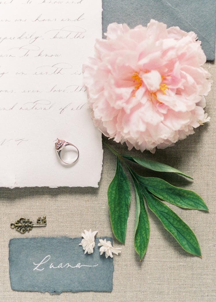 Ring On Top Of Letter Beside Pink Flower