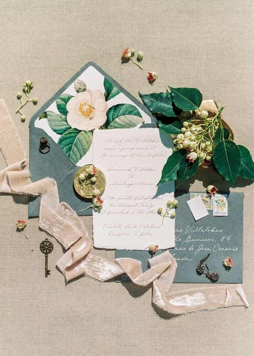 Free An artistic arrangement of a floral envelope, vintage key, and decorative ribbon on a textured surface. Stock Photo