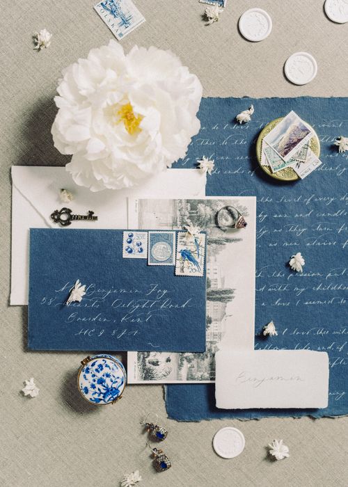 Free Flat lay of vintage stationery with blue paper, white flower, and postage stamps. Stock Photo