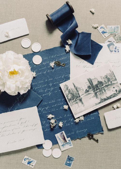 Free An artistic flat lay of vintage stationery, blue ribbon, and white florals for creative design inspiration. Stock Photo
