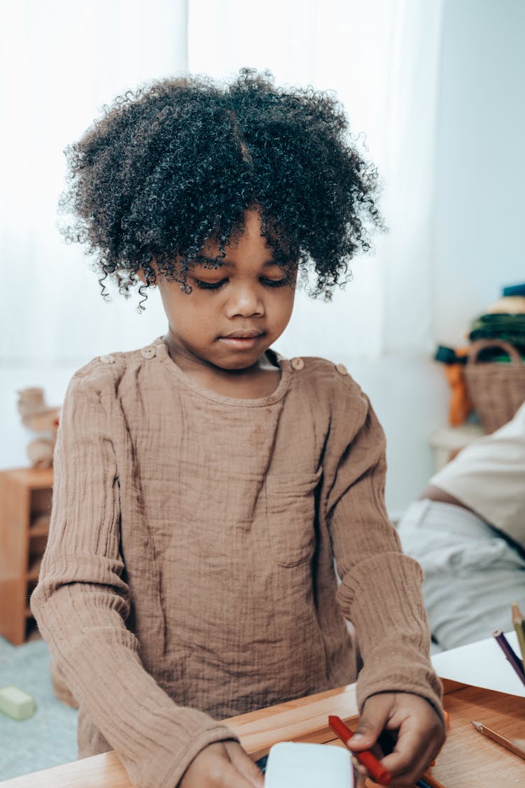 Charming African American Girl Sitting With Felt Pen And Paper Cube