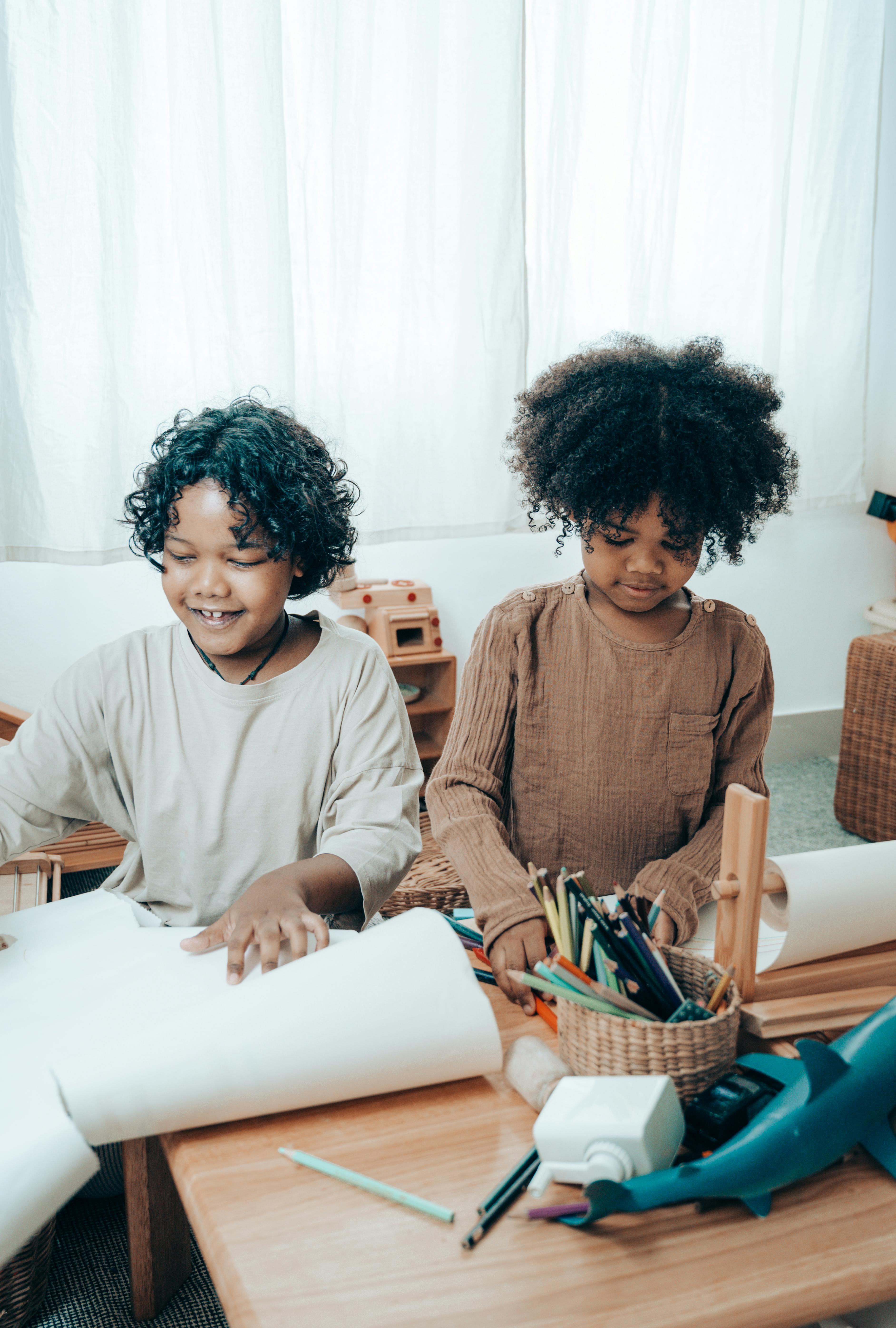 Happy black children sitting at table with paper sheets \u00b7 Free Stock Photo