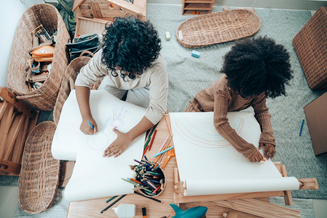 Free Faceless African American siblings drawing on blank papers at home Stock Photo