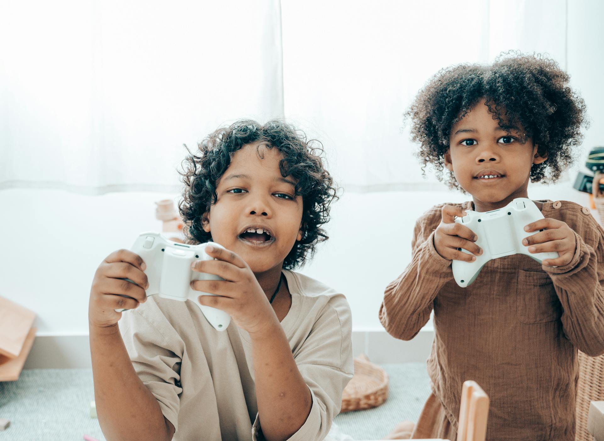 Cheerful black children playing with game pads in room