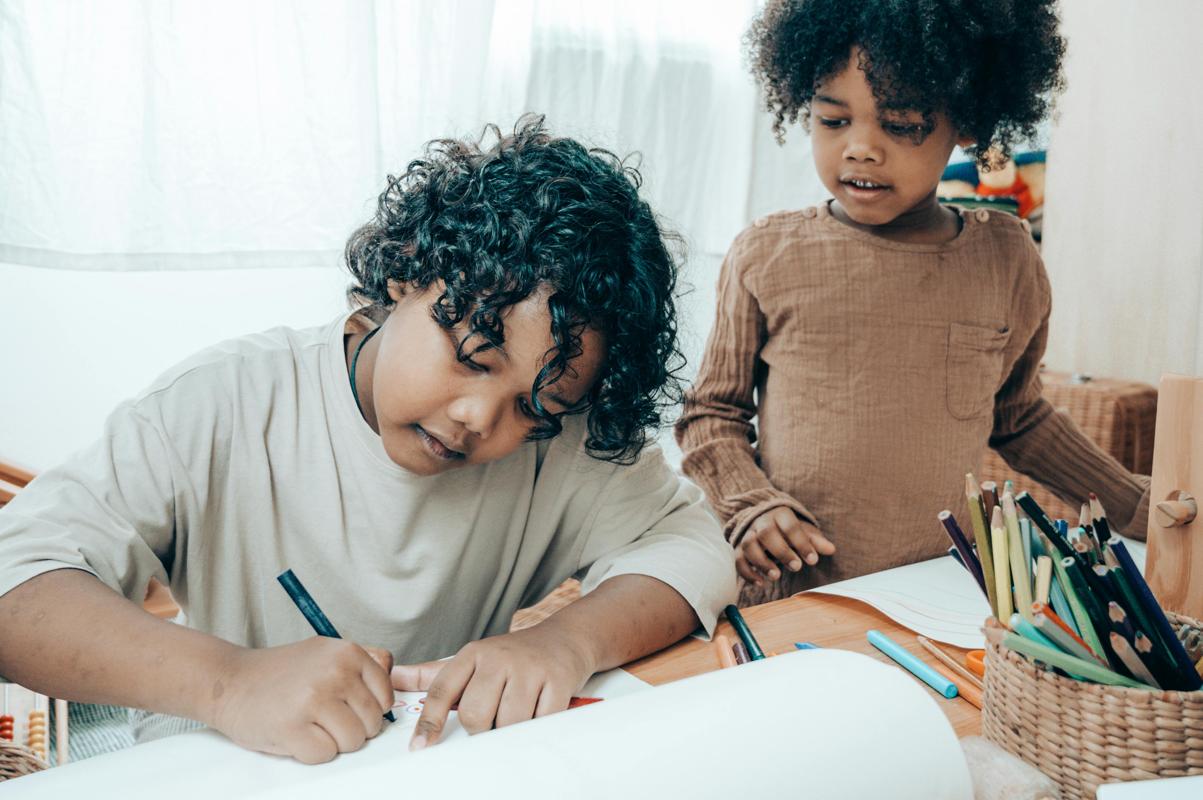 african american siblings drawing on blank paper in apartment