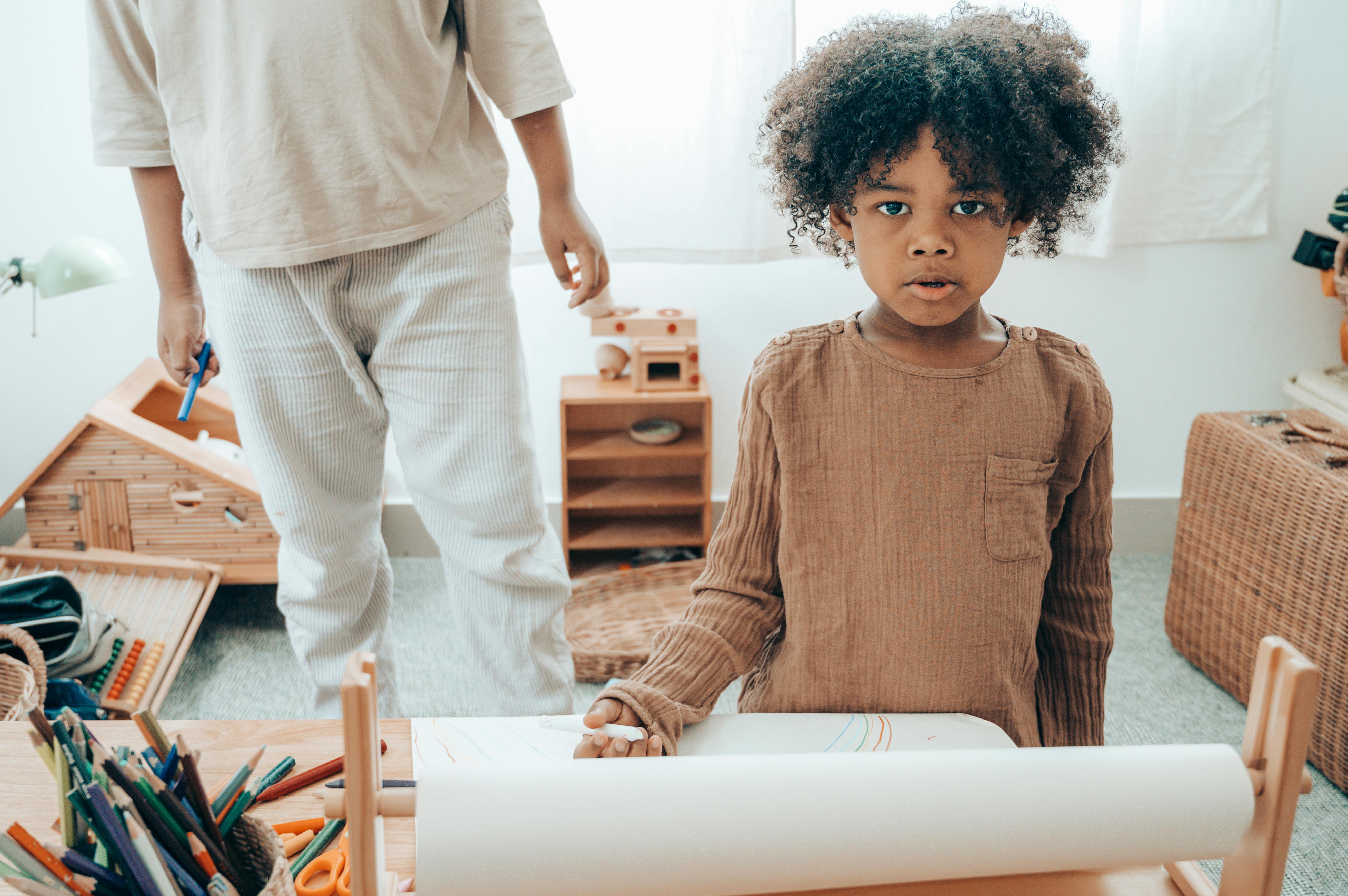 modest african american girl with paper near crop sibling at home