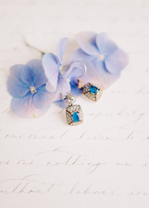 Earrings on Flowers on a White Surface with Writings
