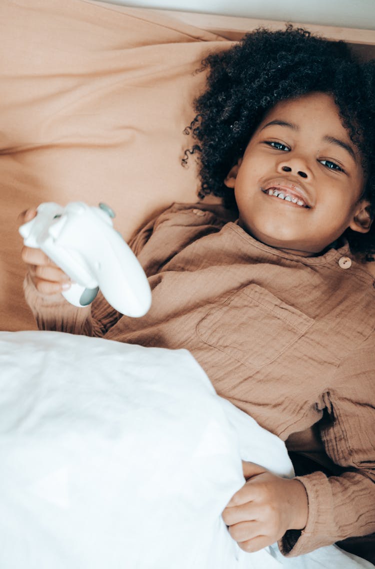 Cheerful Black Girl Playing With Joystick In Bed In Morning