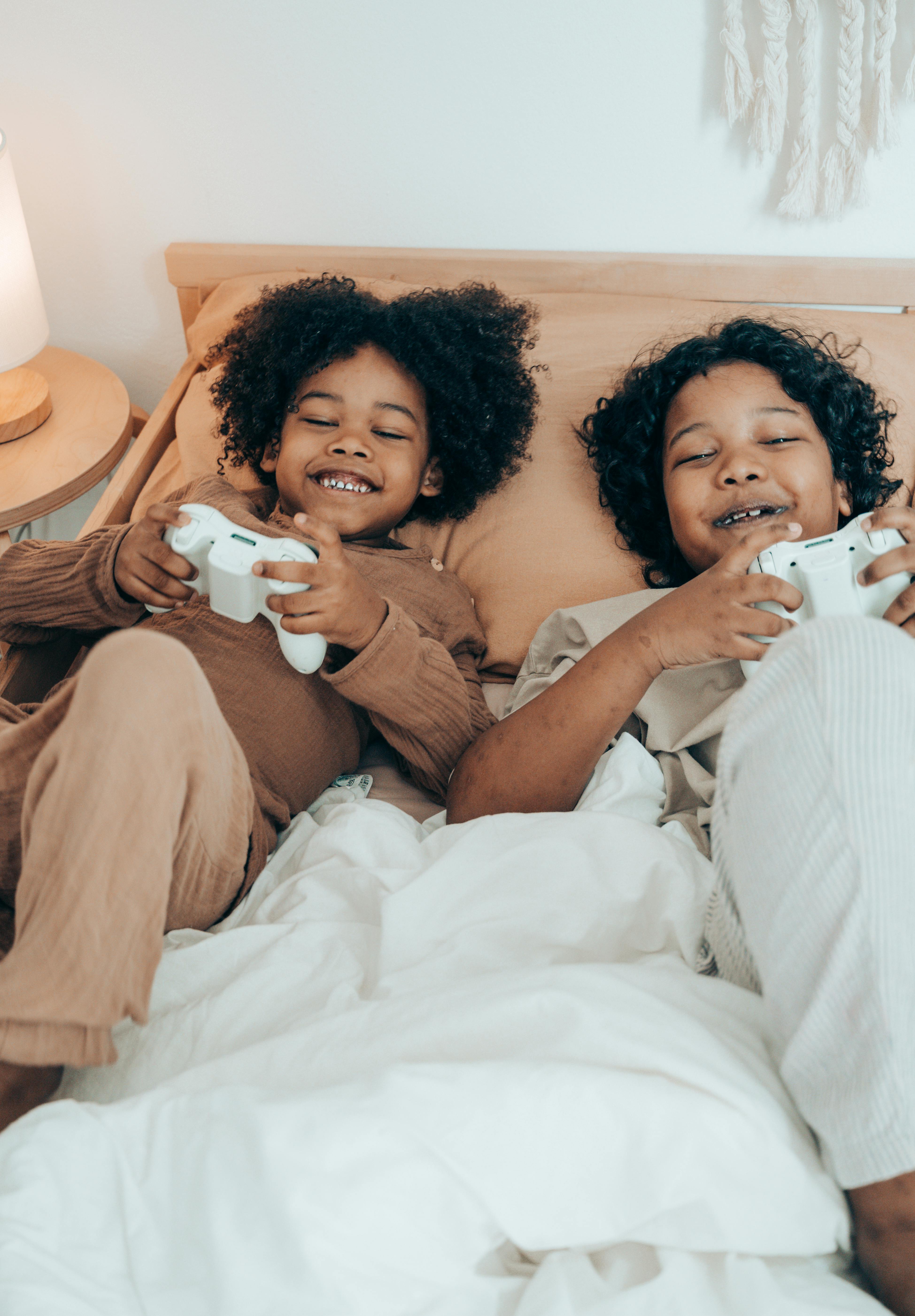 cheerful black kids resting on bed in morning