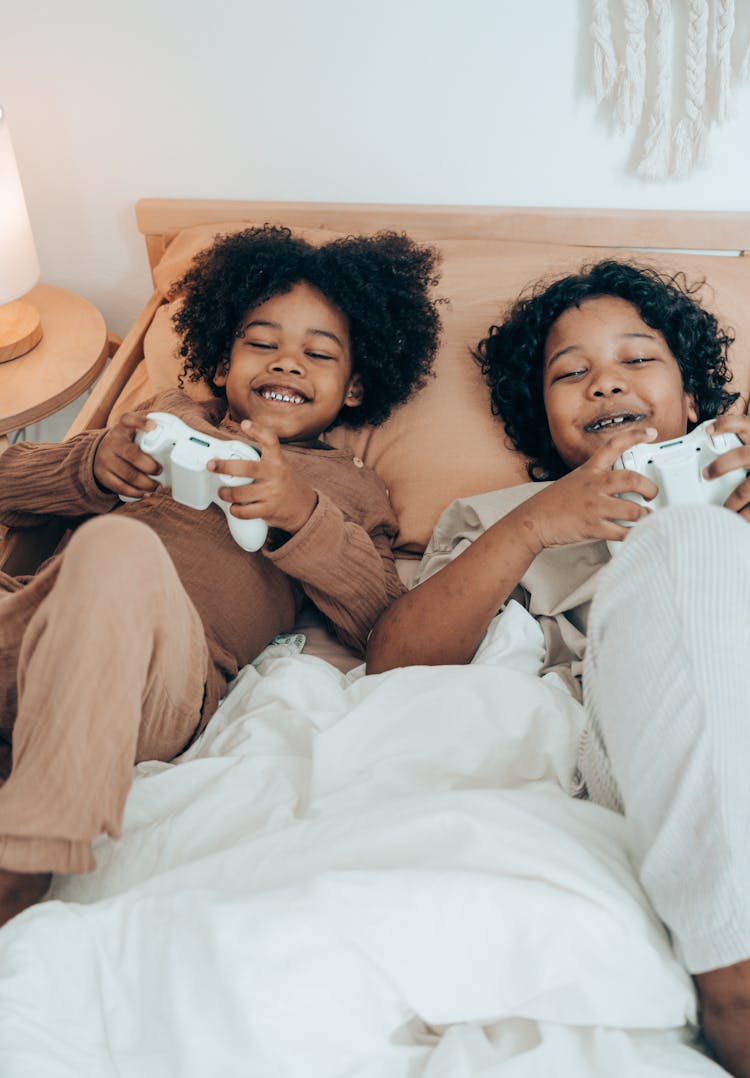 Cheerful Black Kids Resting On Bed In Morning