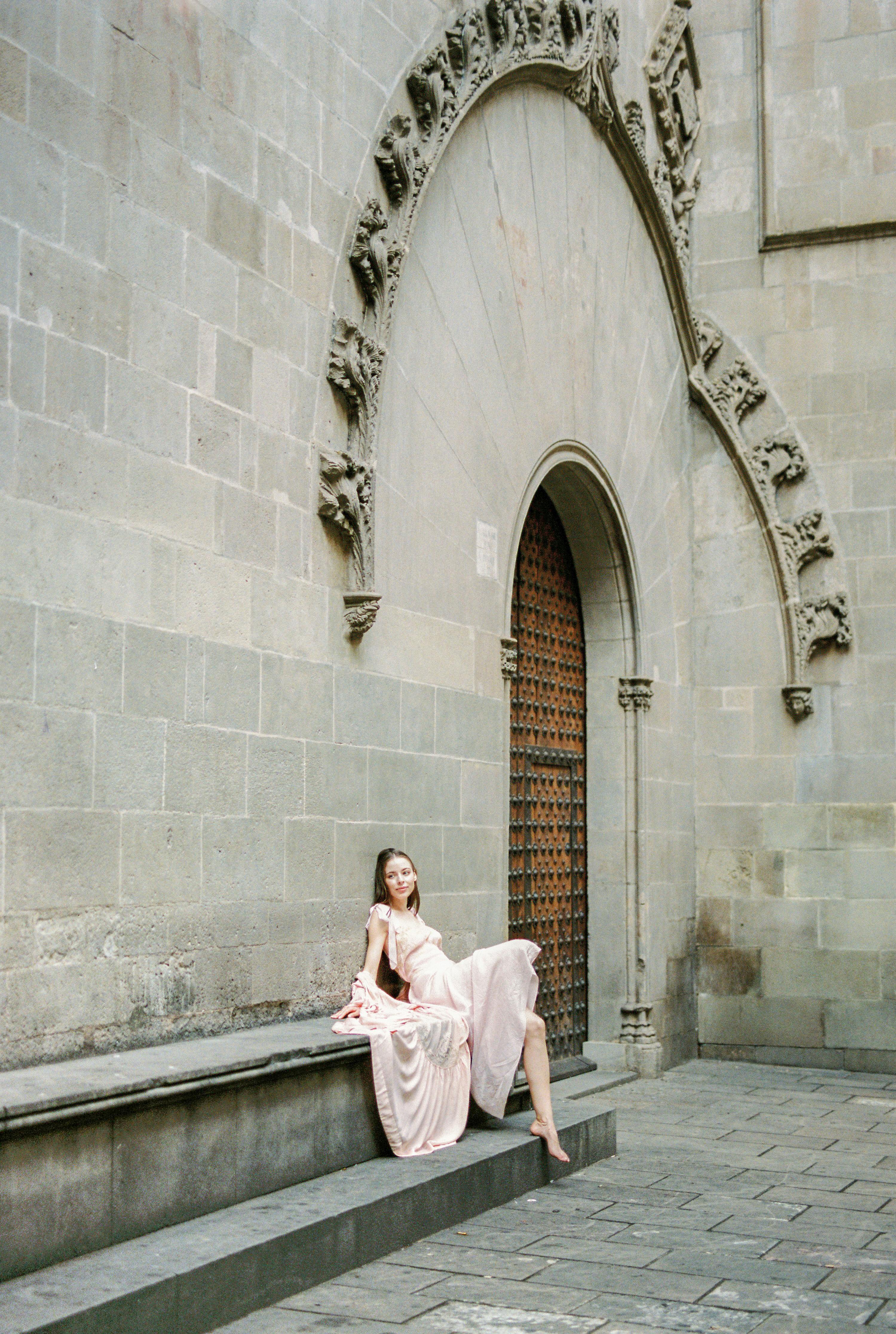 woman in pink long sleeve dress sitting on gray concrete bench