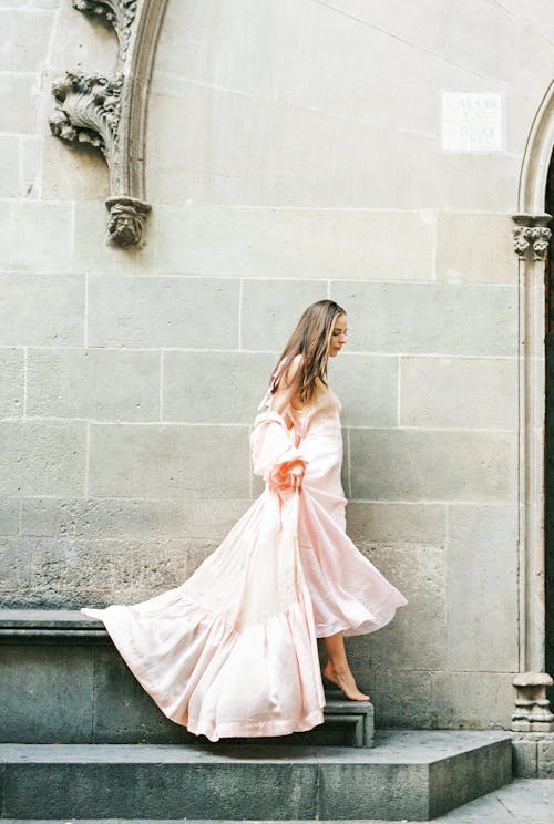 Femme En Robe à Manches Longues Blanche Debout à Côté Du Mur De Béton Gris