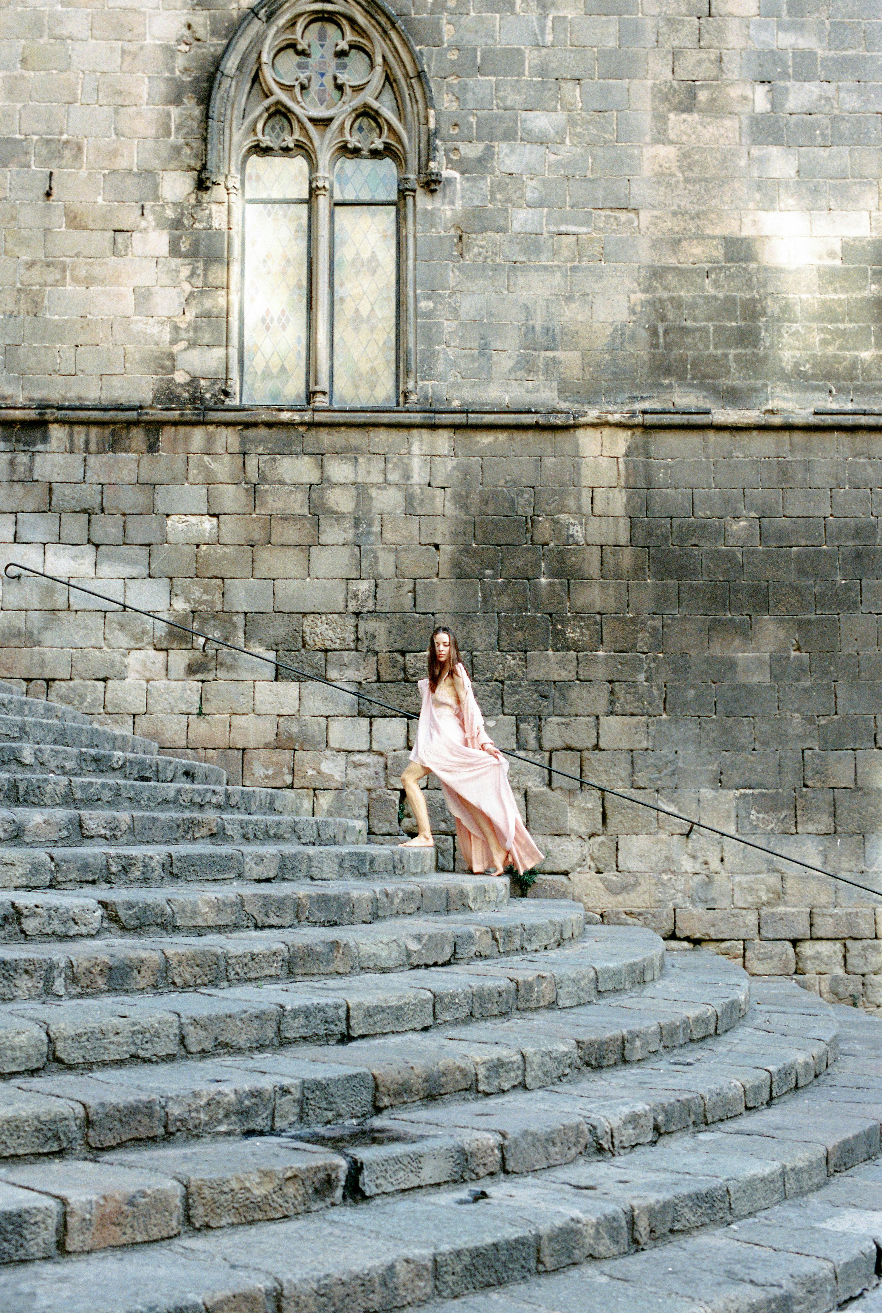 woman in pink dress standing on concrete stairs