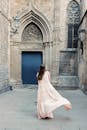 一位身着飘逸连衣裙的女子，在历史悠久的哥特式建筑中旋转