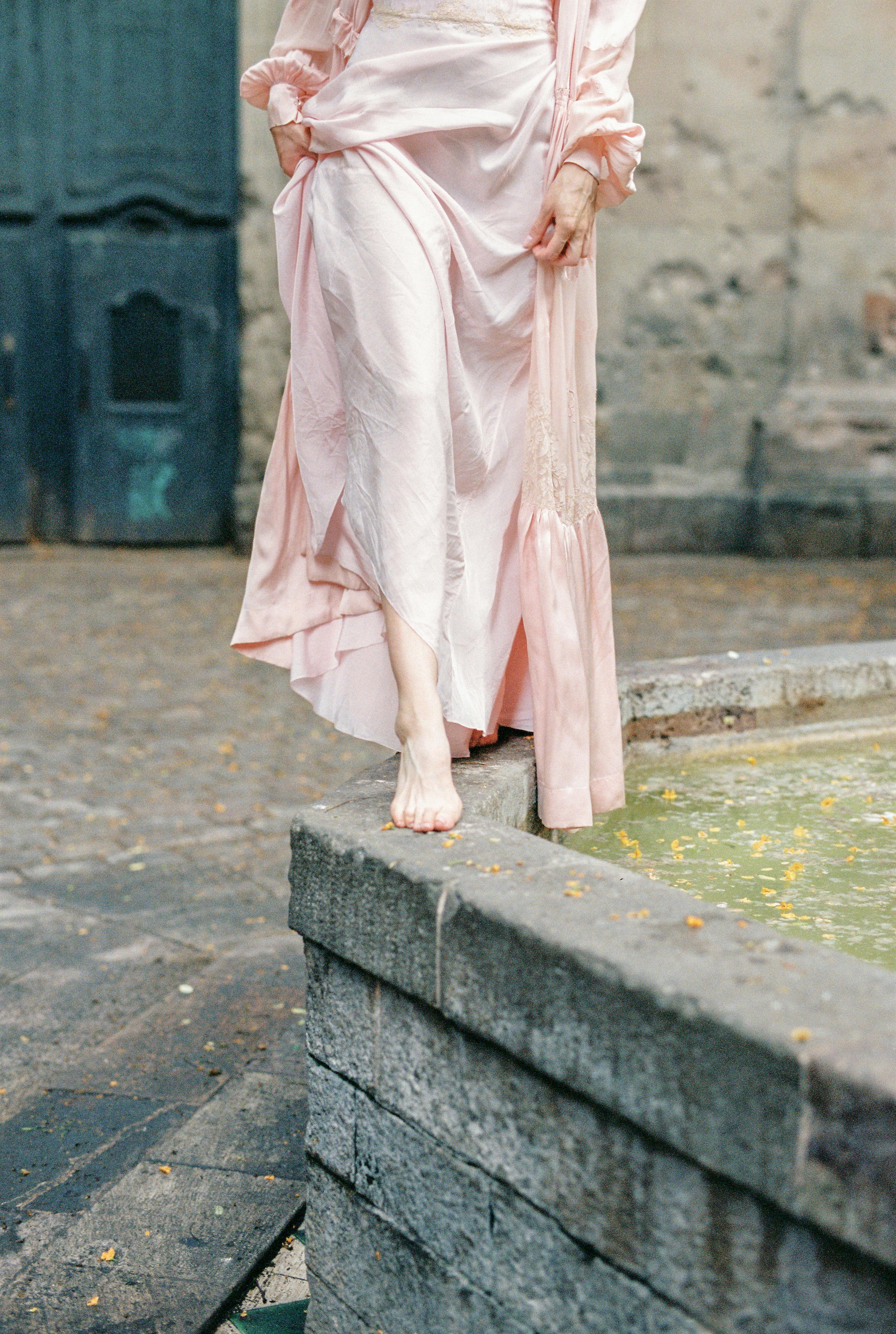 woman in pink dress standing on gray concrete floor