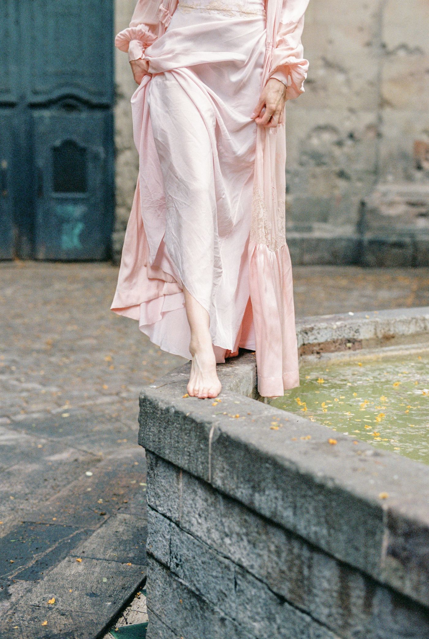 A person in a pink dress standing on a gray concrete floor — minimal editorial blush styling