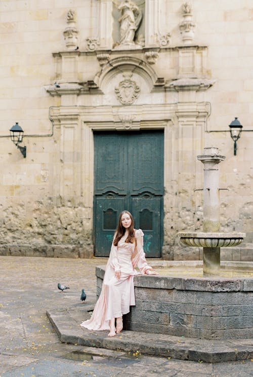 Woman in Pink Dress Sitting near the Fountain