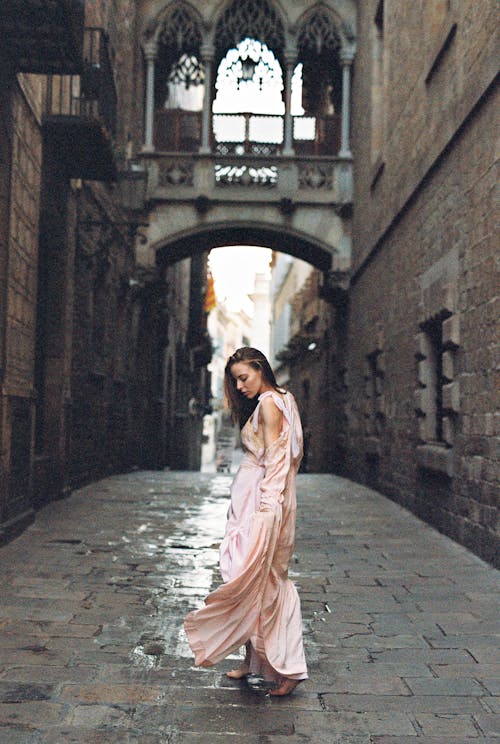 Женщина в розовом платье стоит на сером бетонном полу