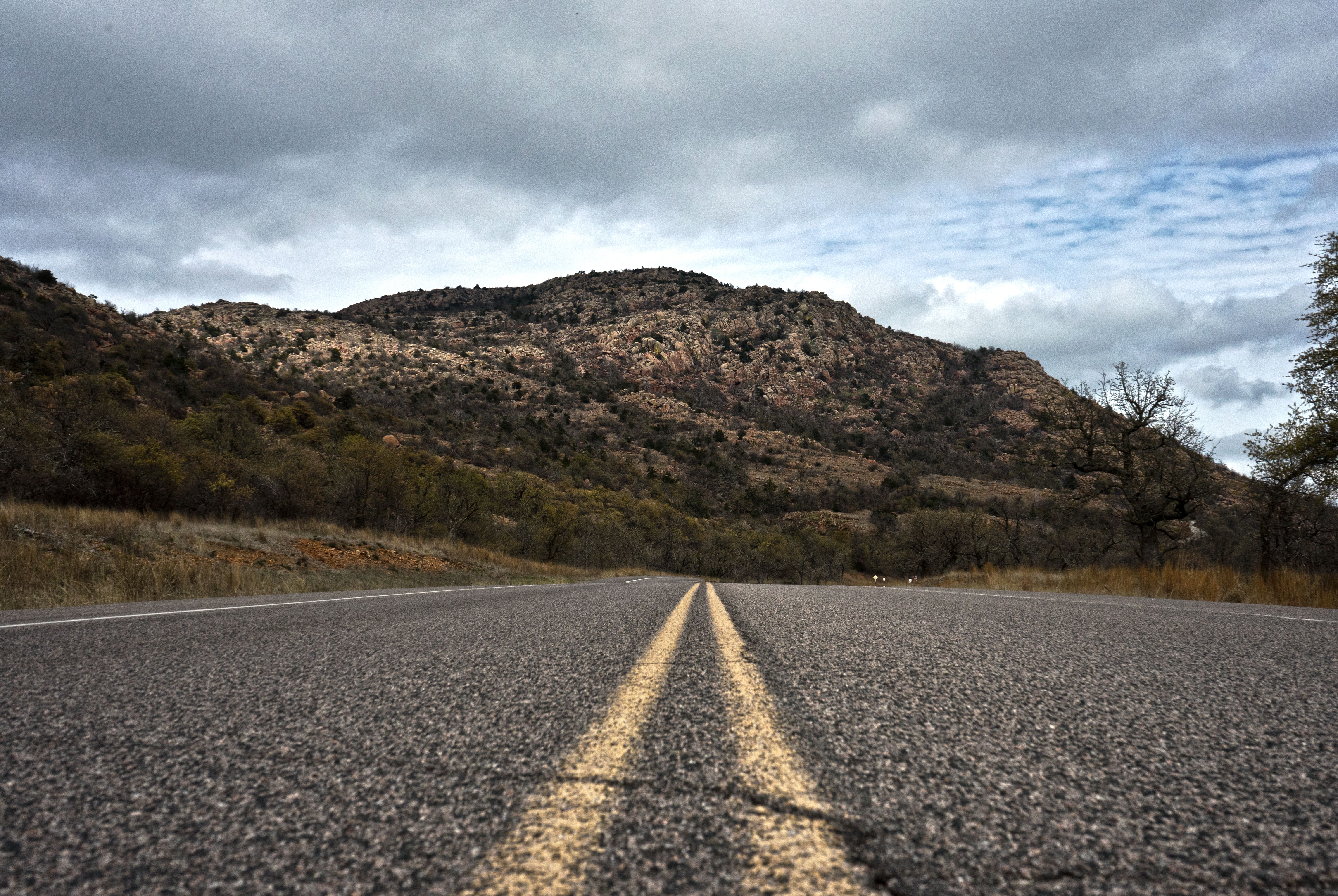 Empty road leading to the scenic Oklahoma mountains under a cloudy sky.