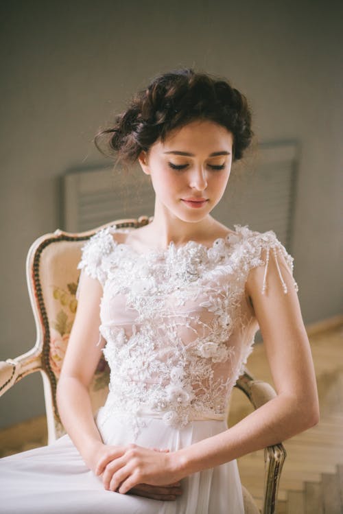 Femme En Robe à Fleurs Blanche Assise Sur Un Fauteuil En Bois Marron