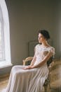 一位穿着优雅礼服的老练新娘，优雅地坐在窗边
