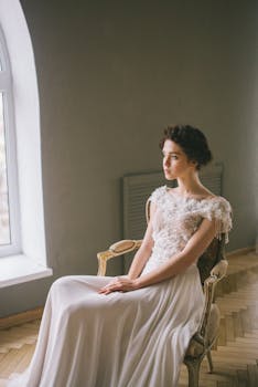 一位穿着优雅礼服的老练新娘，优雅地坐在窗边