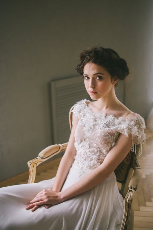 Woman in White Floral Dress Sitting on Wooden Armchair