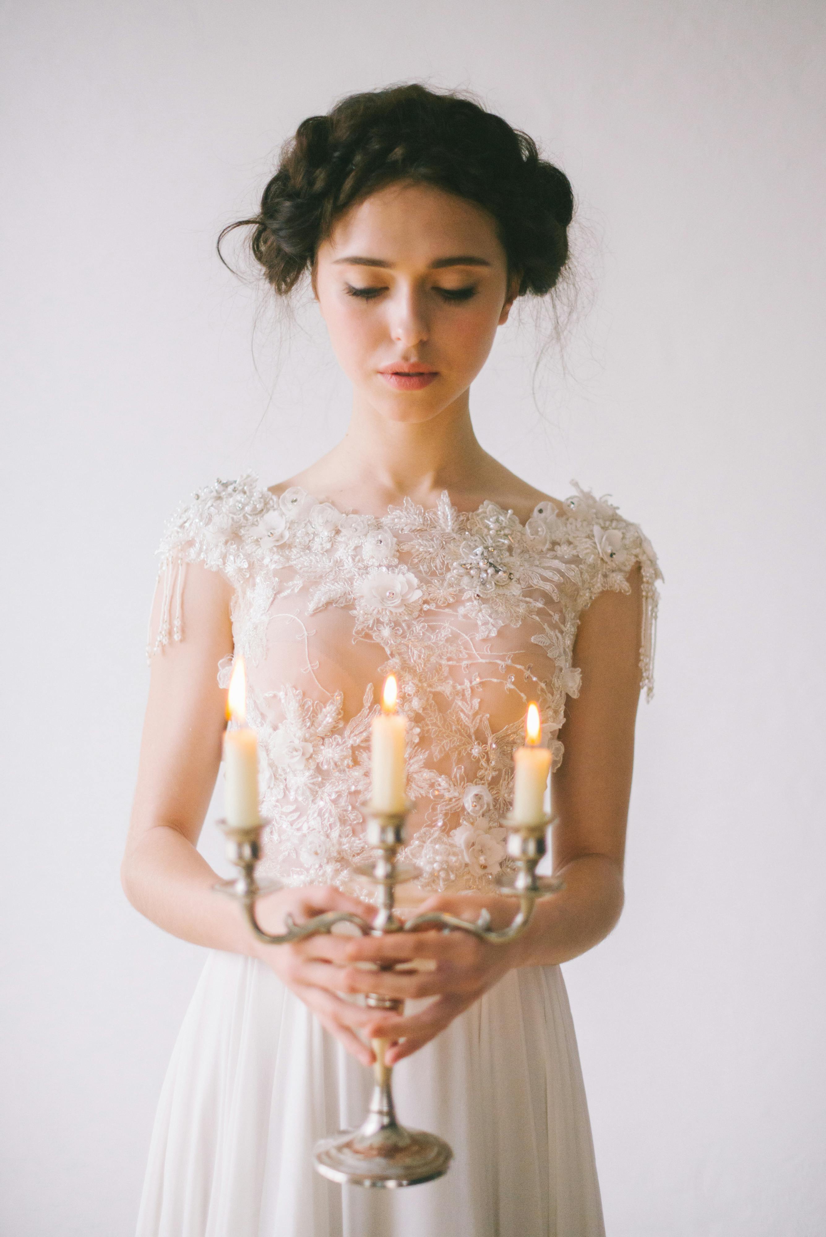 一位身穿白色连衣裙的新娘手持优雅烛台，肖像宁静，散发着优雅气质