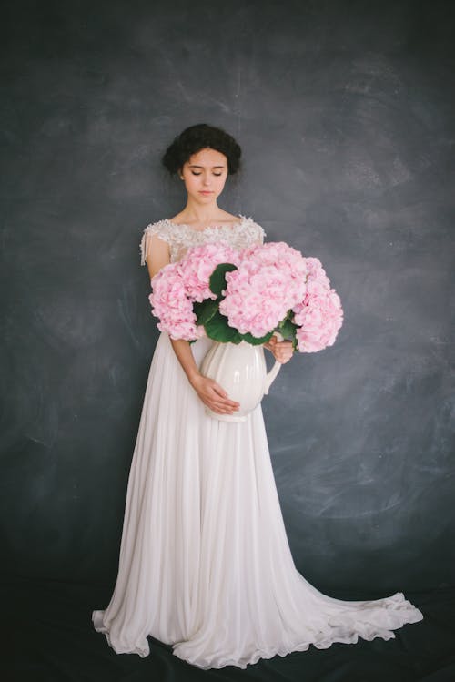 A Female Model Holding a Vase with Pink Flowers