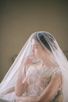 A serene portrait of a bride in a delicate lace wedding dress with a flowing veil.
