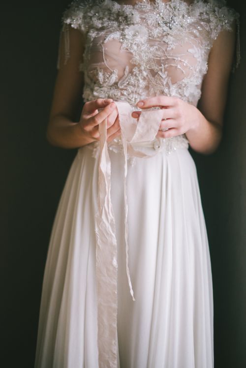 Free A delicate bridal gown featuring lace and a flowing sash, showcasing intricate fashion design. Stock Photo