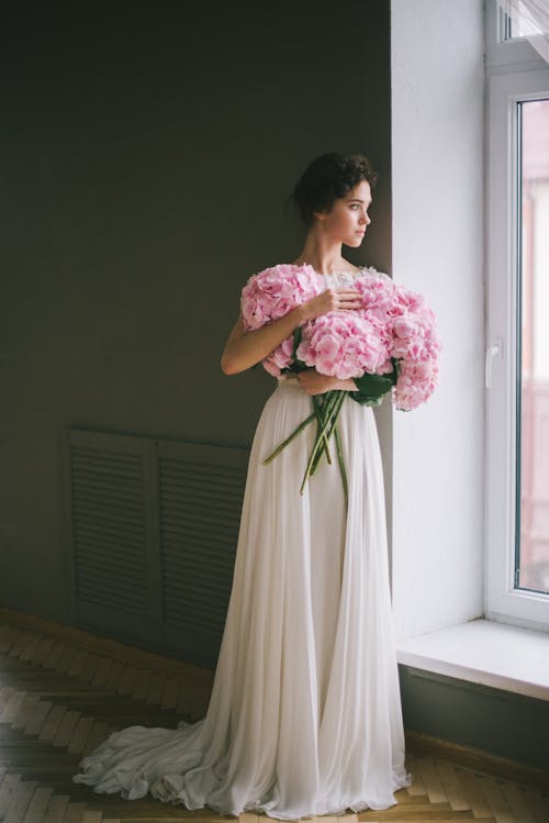 Free A Woman in a Wedding Dress Standing by a Window  Stock Photo