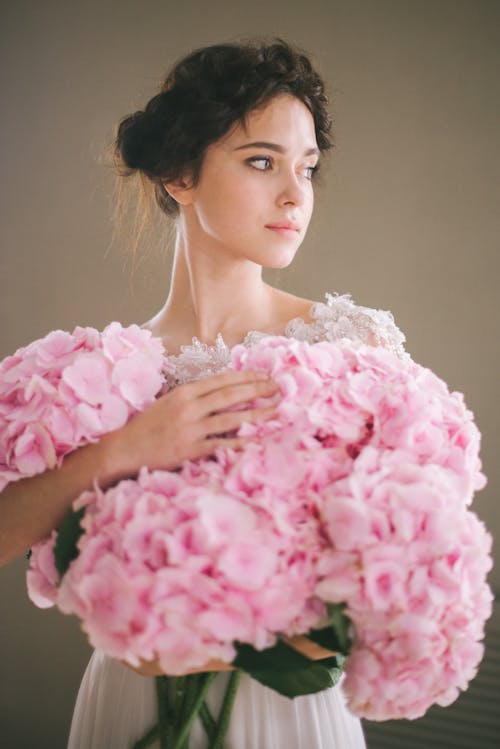 A Young Woman Holding a Bunch of Pink Flowers