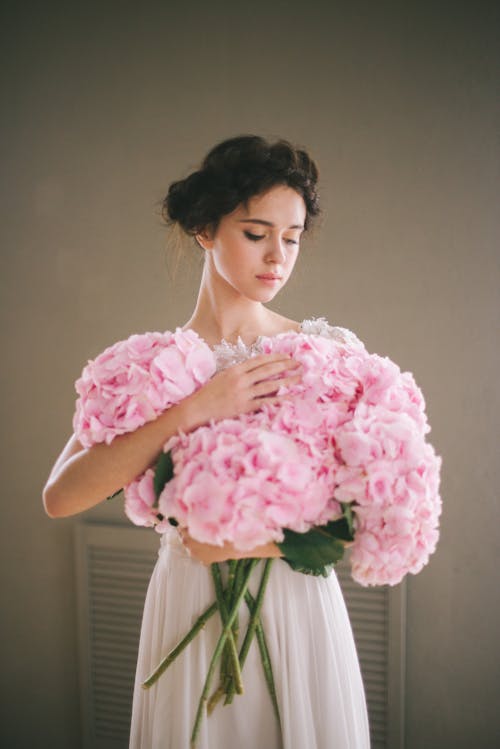 ピンクの花の花束を保持しているピンクの花柄のドレスの女性