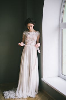 一位穿着优雅蕾丝婚纱的新娘在窗前优雅地摆着姿势