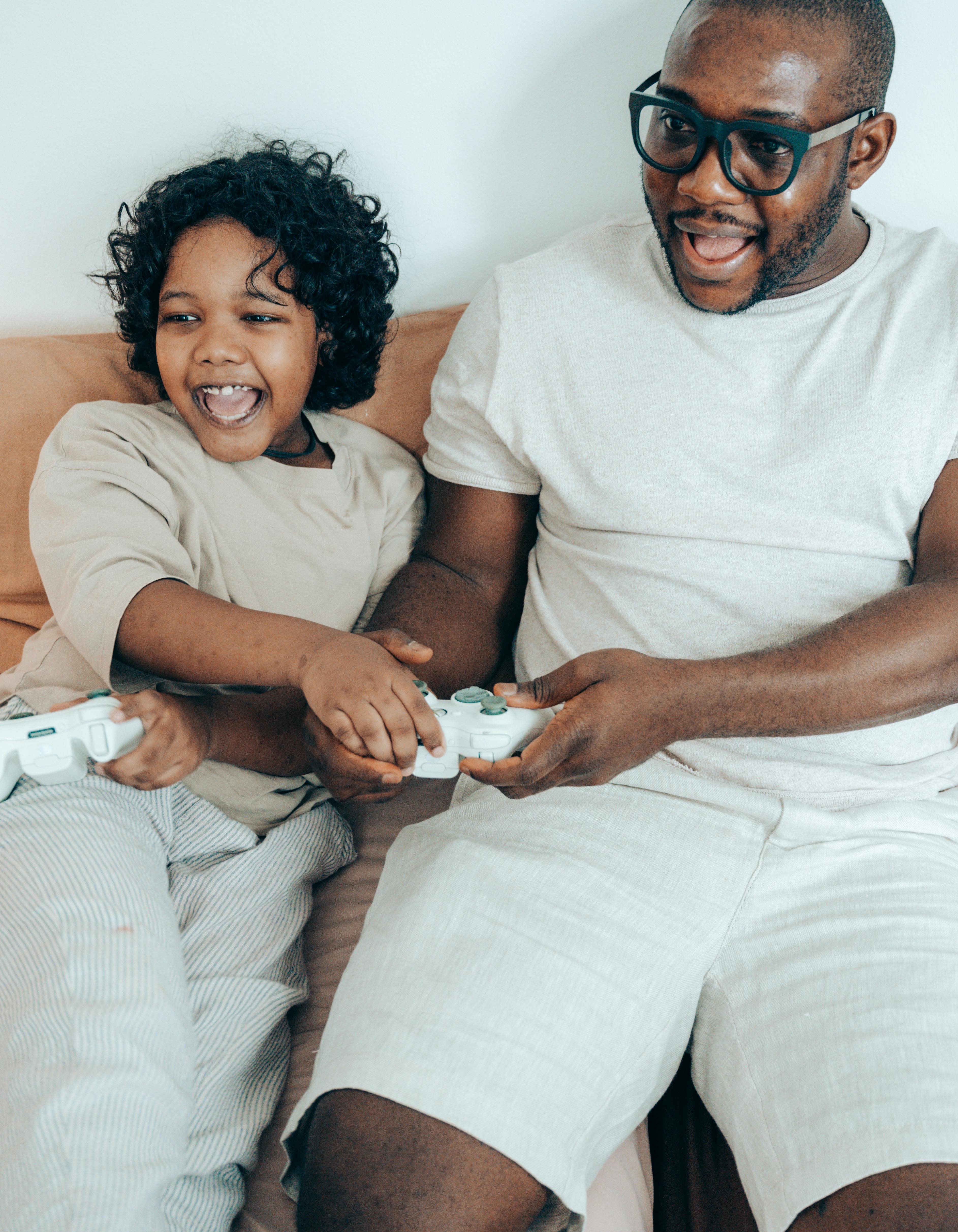 happy black father and kid playing video game at home