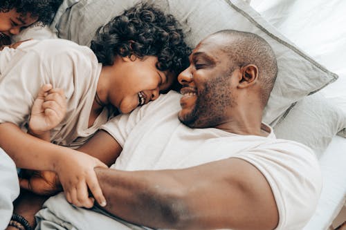 Laughing black father playing with children