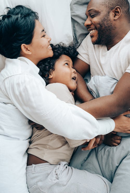 Free Happy ethnic family hugging each other in bed Stock Photo