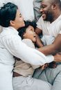 Happy ethnic family hugging each other in bed