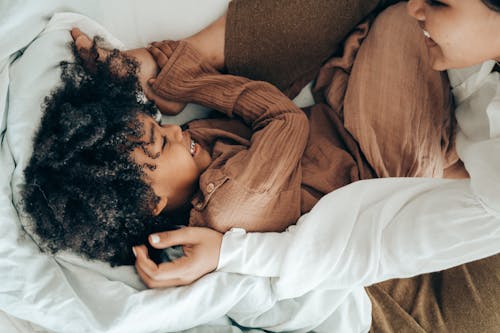 Free Happy ethnic kid playing with mom on bed Stock Photo