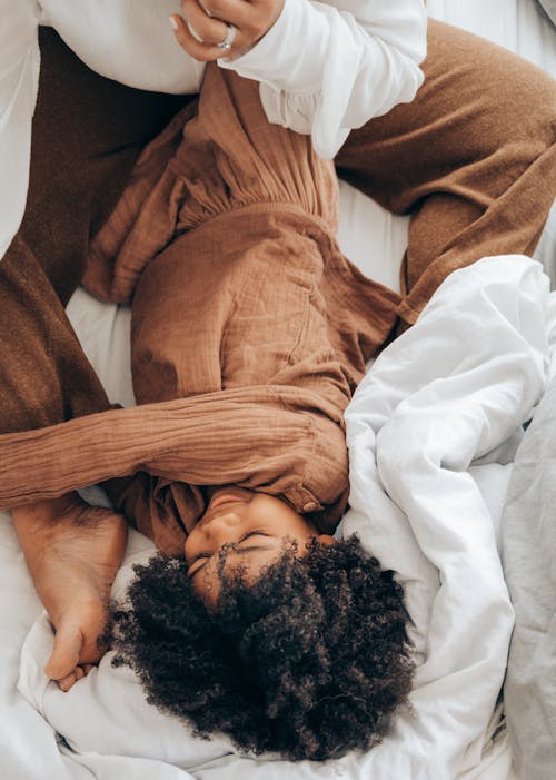 Free African American kid playing with mother on bed Stock Photo